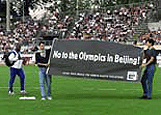 Cuba's Emeterio Gonzales (L) passes two demonstrators showing a banner which reads "No to The Olympics in Beijing" during the Lausanne athletics meet on Wednesday.