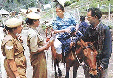 A woman pilgrim from Ahmedabad with an artificial lower limb due to the January 26 earthquake is frisked by women police officials as she starts her ride to the holy Amarnath Cave at Chandanwari, 113 km from Srinagar.