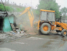 An MC bulldozer razes several jhuggies to the ground along the Jagraon bridge alignment in Ludhiana on Friday. 