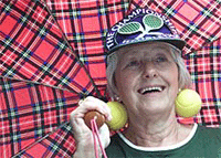 A tennis fan shelters from the rain under a tartan umbrella at Wimbledon on Saturday. Rain delayed the start of play on Saturday.