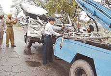 Policemen tow away the badly damaged Mahindra jeep to clear the road after the vehicle collided with a bus near Ludhiana on Sunday.