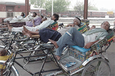 Away from the heat, rickshaw-pullers relax under a shed outside Rohtak railway station. 