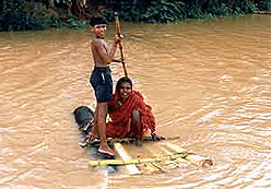 A boy pushes a makeshift raft carrying his mother through floods in Jajpur district of Orissa on Tuesday.