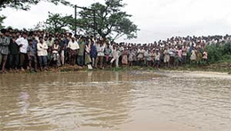 Villagers gather on an embankment to watch rising floodwater in the eastern Indian state of Orissa on Thursday.
