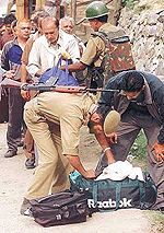 An Indian policeman checks the belongings of a Hindu pilgrim before allowing him to move ahead towards the Holy cave of Amarnath
