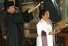 Megawati Sukarnoputri, right, has a Quran held over her head by an unidentified religious affairs official during her swearing-in as the nation's fifth president at parliament in Jakarta, Indonesia on Monday. 