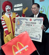 McDonald's Co (Japan) Ltd President Den Fujita holds a model of stock certificate.