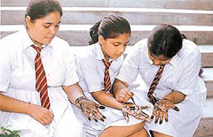 Students apply mehndi on their hands.