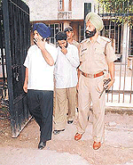 Two constables, Davinder Singh and Mahinder Singh, cover their faces while coming out of the District Court complex in Chandigarh. 