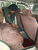 A Pakistani police official inspects the bloody floor inside a car 
