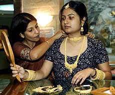 A saleswoman helps a customer try on new gold jewelery introduced by a firm belonging to India's premier Tata business group, in Calcutta on Wednesday.