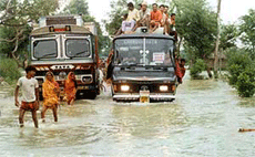 Passengers travel on a bus rooftop through a flooded street in Patna on Saturday. The Army has been called in to help in relief and rescue operations in the area where floods have displaced nearly half a million people, officials said on Saturday.