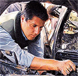 A Palestinian policeman inspects the rubble of a car.