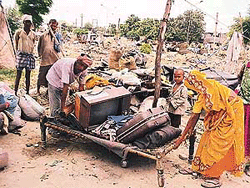 The family of a migrant worker collects its belongings after a demolition drive.