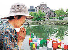 Toshie Kanda, 70, offers a prayer for atomic bomb victims after releasing a floating paper lantern at Hiroshima's Motoyasu river