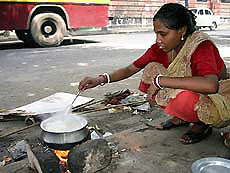 Durga Das prepares lunch for her family on a pavement on a busy street in Kolkata on Tuesday.