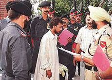 Pakistani border security guards hand over Anat Kumarjee, center, an Indian citizen who illegally entered in Pakistan, to Indian border security officer.