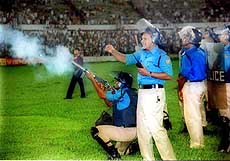 A policeman fires a tear-gas shell.