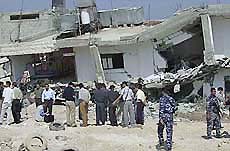 Palestinian police personnel and journalists look at the damage to a police station 