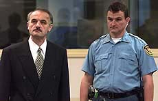 Bosnian Serb army colonel Vidoje Blagojevic (L) is closely watched by an United Nations security officer during his initial appearance at the War Crimes Tribunal for the Former Yugoslavia in The Hague on Thursday. 
