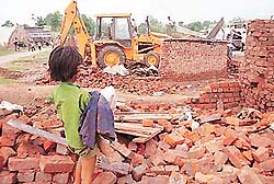 A child looks on as his unauthorised hut is demolished by the HUDA enforcement wing in Rajiv Colony, Sector 16, in Panchkula on Friday.
