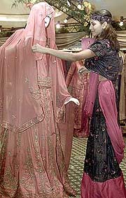 A model adjusts traditional Indian bridal wear on a mannequin