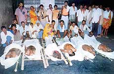 Family members standing by the bodies of six villagers.
