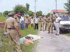 Policemen inspecting a heap of clothes in which a highly decomposed body was found .