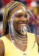 Serena Williams of the United States, smiles as she is framed by the trophy.