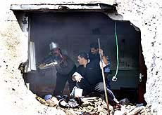 Palestinian security men and firemen inspect damage to a police station after two Israel surface-to-surface missiles hit the station at Khan Younis south of Gaza Strip on Wednesday.