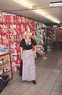 A woman in traditional Volendam costume, receiving visitors at a cheese farm
