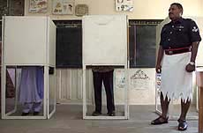 A Fijian policeman oversees voters casting their votes in a converted classroom on the first day of Fiji's general election at Maigania Muslim School near Nadi in the west of the country on Saturday.
