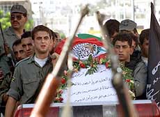 A slain Palestinian security officer is carried by his comrades on the way to his funeral in the West Bank city of Hebron on Tuesday.