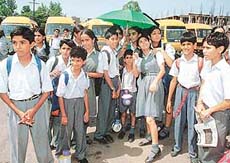 Children wait for their parents to pick them up as buses remain parked in the background in Chandigarh on Monday.