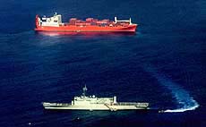 Refugees are transferred by small boat from the Norwegian freighter Tampa (top) to the Australian Navy vessel Manoora off Christmas Island on Monday. 