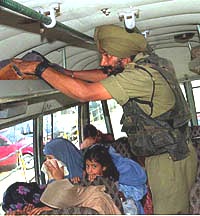 A paramilitary jawan conducts a search inside a passenger bus 