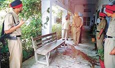 Policemen examine the spot where a school watchman was killed