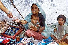 An Indian customer buys a zodiac stone from a street vendor .