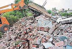 A JCB machine demolishes unauthorised structures in Raipur Khurd village on the Chandigarh-Ambala highway on Monday. 