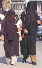 Veiled Kashmiri Muslim women walk on a street.