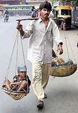 A street performer carries his young sidekick and musical instruments down a Kolkata street on Tuesday.