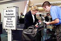 Delta Airlines representative Jeremy Holland (right) checks a passenger's ID against her boarding pass before allowing her through the metal detectors at the gate area at DFW International Airport on Thursday. 