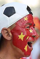 A Chinese soccer fan, wearing a cap in the shape of a soccer ball and with a national flag painted on his face, arrives at the Wulihe Stadium in Shenyang, Liaoning province, on Saturday for tonight's World Cup Soccer qualifying match against Uzbekistan.