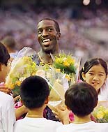 Five-time Olympic champion Michael Johnson of the USA receives flowers from schoolchildren after racing as the anchor in the mens medley relay at the Super Track and Field Meet 2001 at International Stadium Yokohama, south of Tokyo on Saturday. 