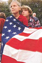 Caitlyn McCrone (left) and her sister, Chelsea, both from Kent, Washington, drape themselves in the American flag while attending a flower vigil where more than 30,000 people gathered at the Seattle Centre International Fountain on Sunday. 