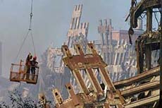 Two rescue workers, suspended from a crane in a basket, survey the World Trade Center wreckage in New York on Sunday.
