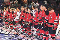 New York Rangers players stand with New Jersey Devils players during the singing of "America the Beautiful" 