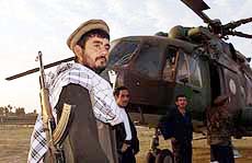 A Northern Alliance soldier keeps watch as he guards a helicopter at Khudja Bahaoudin in Northern Afghanistan on Saturday.