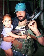 An activist of Ikhwan, the counter-insurgent group fighting against militants alongside the security forces, holding his baby inside a camp in Anantnag.