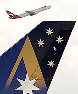 A Qantas passenger jet passes above the tail of a parked Ansett jet as it takes off at Sydney domestic airport on Tuesday.